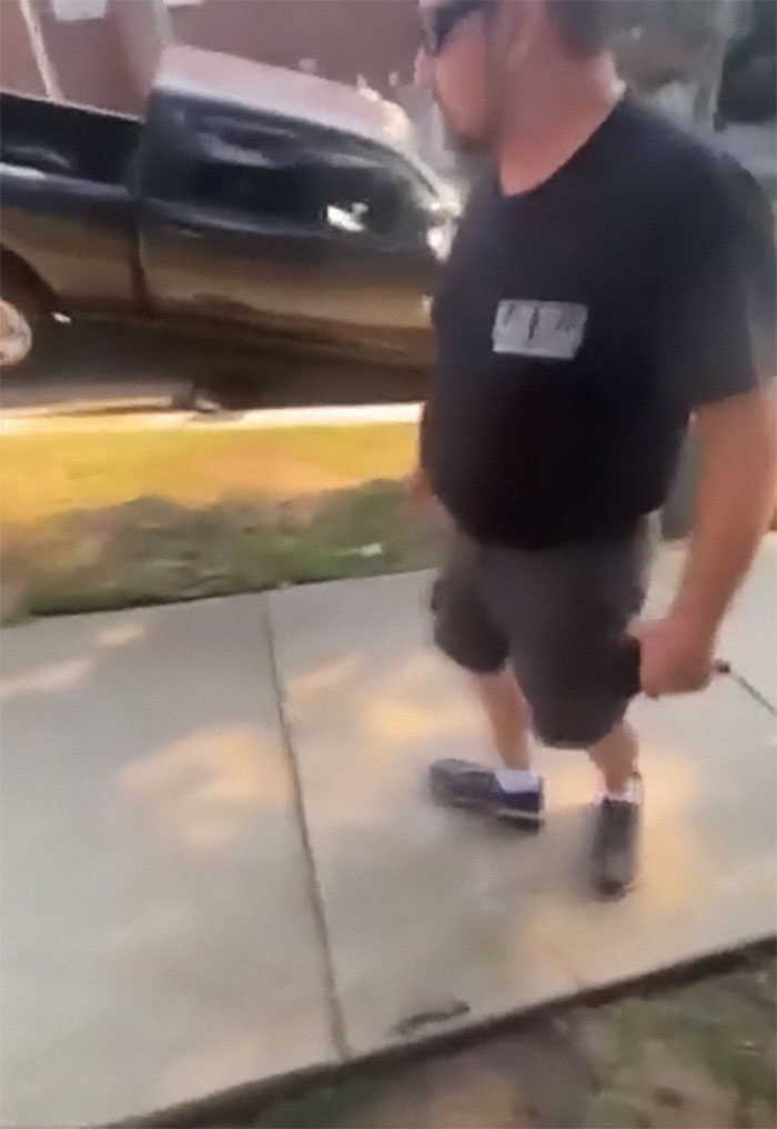Man standing next to a sidewalk near a truck showing instant karma after refusing sinkhole warning due to color bias