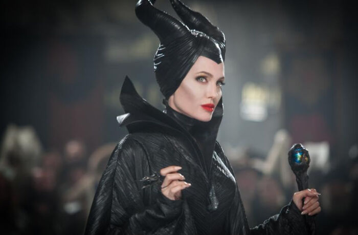 Actress portraying Maleficent in dark costume holding a staff, representing Disney movies poll theme.