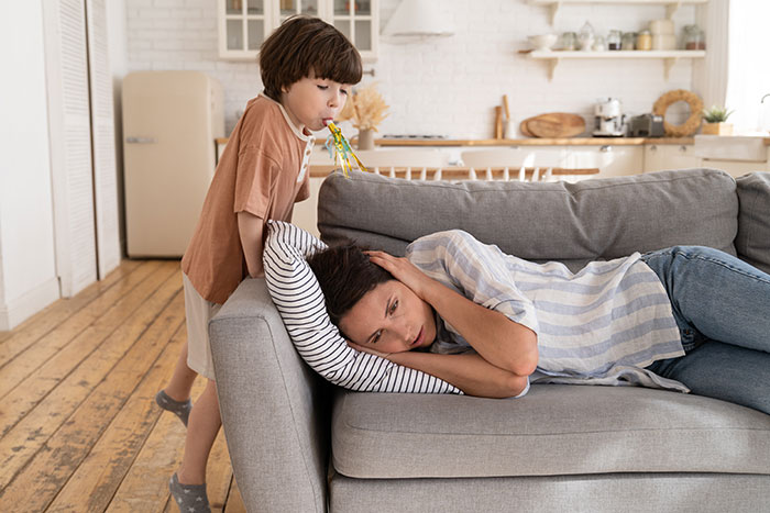 Child whispering anonymous confessions to a woman lying on a couch in a cozy living room setting.