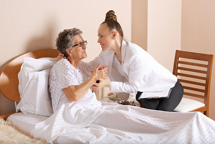 Young woman comforting elderly patient in hospital bed, illustrating anonymous confessions with potential to ruin lives.