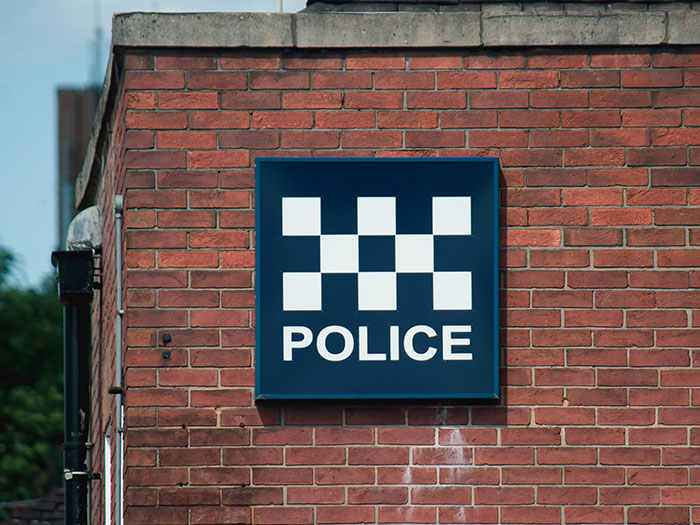 Police sign on a brick building symbolizing safety measures in unsafe neighborhoods and areas to look out for.