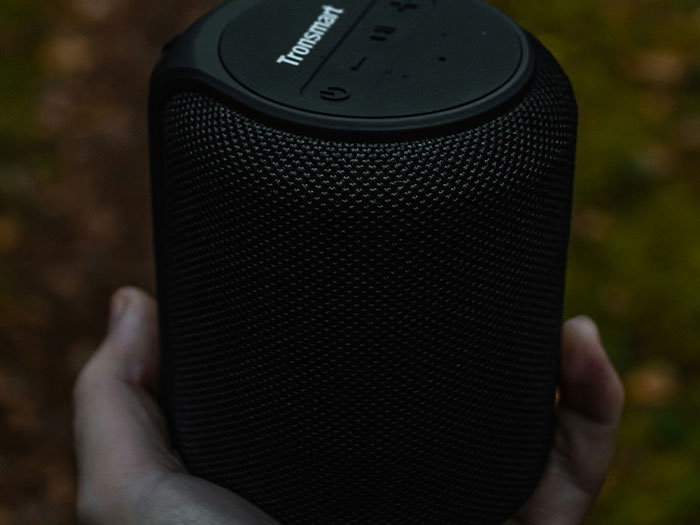 Hand holding a black Tronsmart speaker outdoors, symbolizing signs to look out for in unsafe neighborhoods.