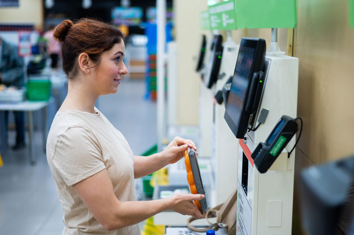 Woman using self-checkout in grocery store, borrowing everything but the kitchen sink, and expecting neighbor to pay bill Woman using self-checkout in grocery store, borrowing everything but the kitchen sink, and expecting neighbor to pay bill