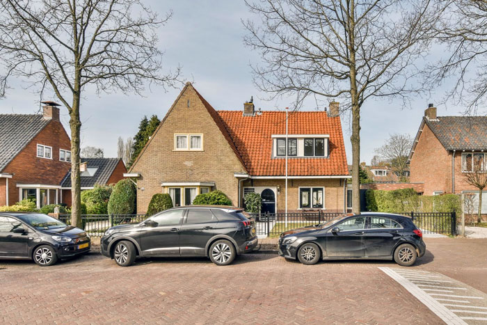 Three cars parked on a public road in front of a house where a man wrongly claims it as personal parking space