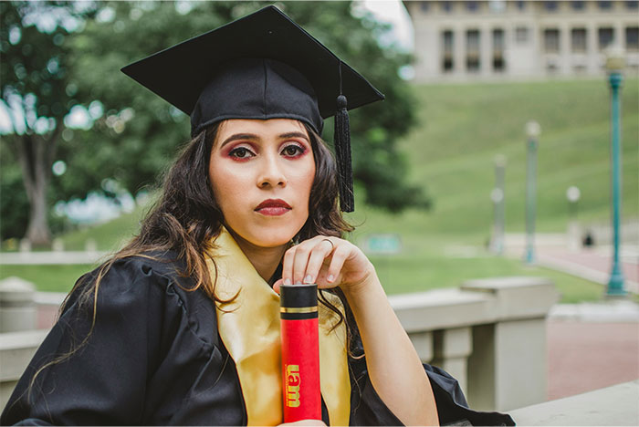 Young woman in graduation gown and cap holding diploma, representing aunt with PhD expecting family to call her doctor. - 1