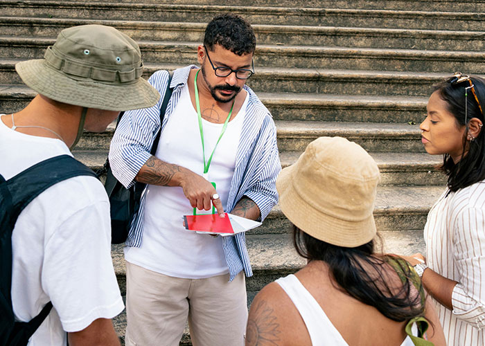 Tour guide showing map to group of tourists on stairs, highlighting family tour amidst childfree couple controversy. - 1