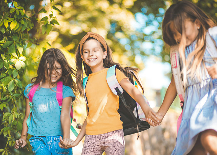 Three girls holding hands and walking outdoors, representing family tour experiences amid childfree couple controversies. - 6