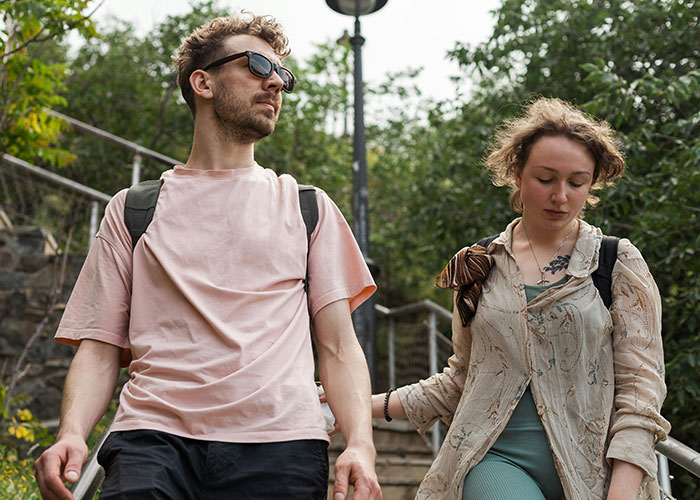 Couple walking outdoors with backpacks, highlighting controversy over tour company and bad reviews for childfree visitors. - 12