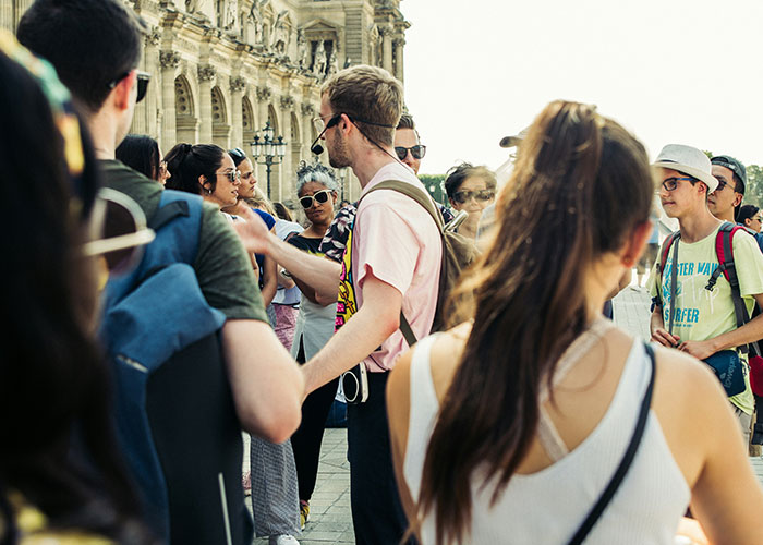 Tour company guide speaking to diverse group of tourists outside historic building during a family tour experience. - 17