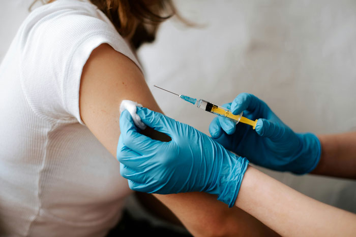Gloved hands holding a syringe preparing to inject a substance into a person’s upper arm for tooth regrowth research. Gloved hands holding a syringe preparing to inject a substance into a person’s upper arm for tooth regrowth research.