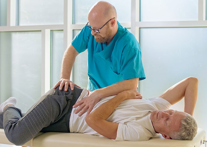 Healthcare professional examining older man’s hip, highlighting seemingly harmless things that are actually very dangerous.