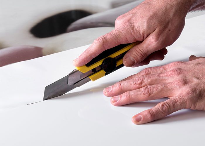 Hands using a utility knife to cut paper, illustrating seemingly harmless things that are actually very dangerous.