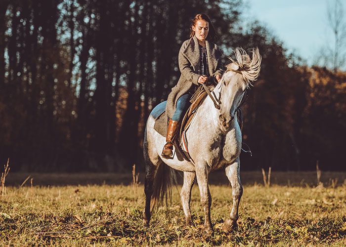Woman riding a white horse outdoors, illustrating seemingly harmless things that are actually very dangerous.