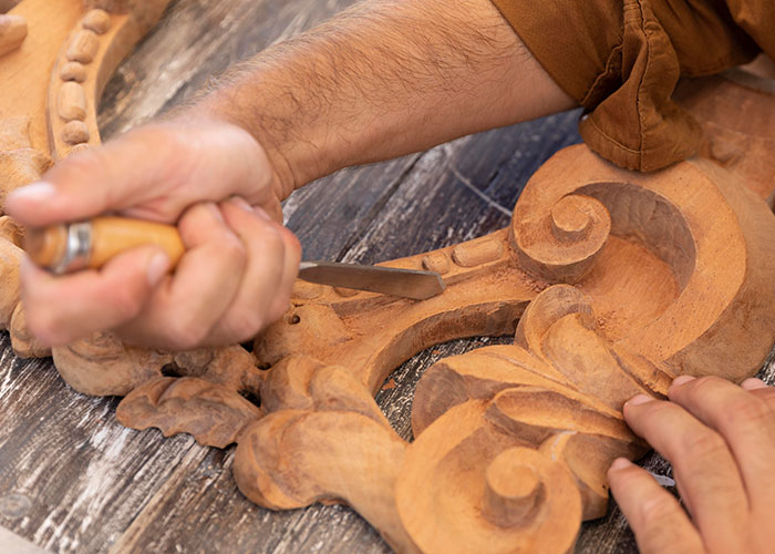 Person using a sharp carving tool on detailed woodwork, illustrating seemingly harmless things that are actually very dangerous.