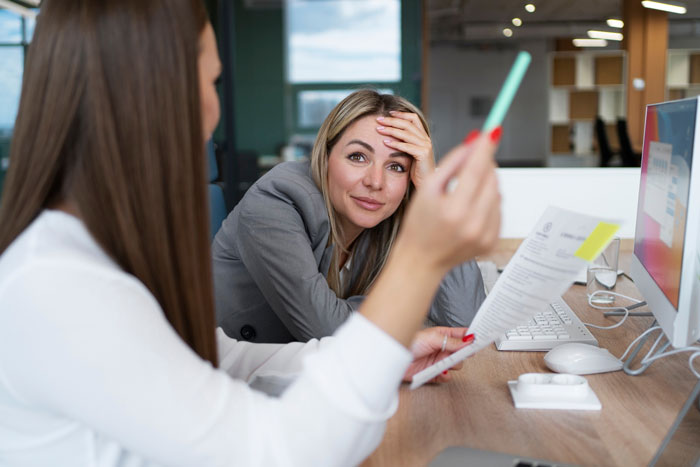 Frustrated worker speaking to colleague in office, showing documents, symbolizing team lead scapegoat and HR complaint issues. Frustrated worker speaking to colleague in office, showing documents, symbolizing team lead scapegoat and HR complaint issues.