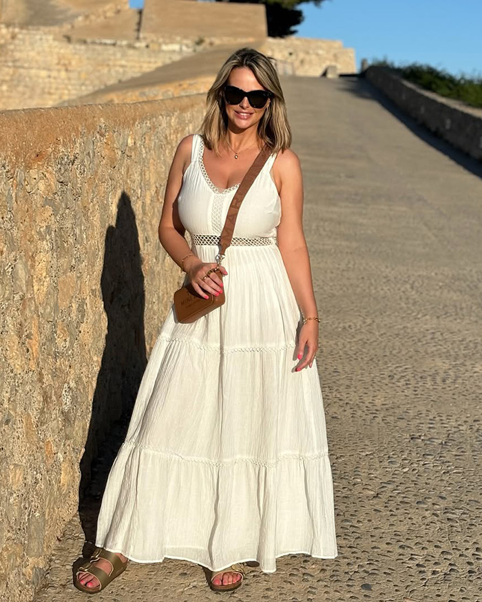 Rhian Sugden posing outdoors in a white dress and sunglasses amid plastic surgery fan backlash and police involvement. Rhian Sugden posing outdoors in a white dress and sunglasses amid plastic surgery fan backlash and police involvement.