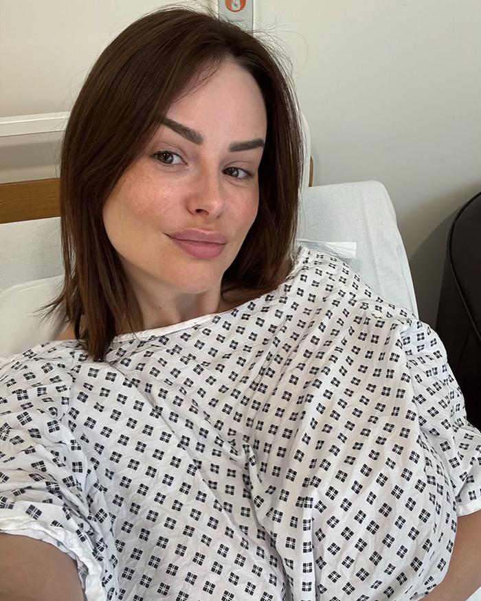 Rhian Sugden in hospital gown taking a selfie amid massive fan backlash over $13K plastic surgery controversy. Rhian Sugden in hospital gown taking a selfie amid massive fan backlash over $13K plastic surgery controversy.