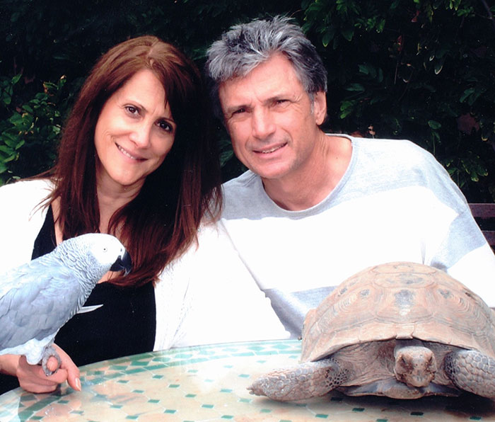 Couple posing outdoors with a parrot and tortoise, related to epic police fail in American Idol exec case. - 1