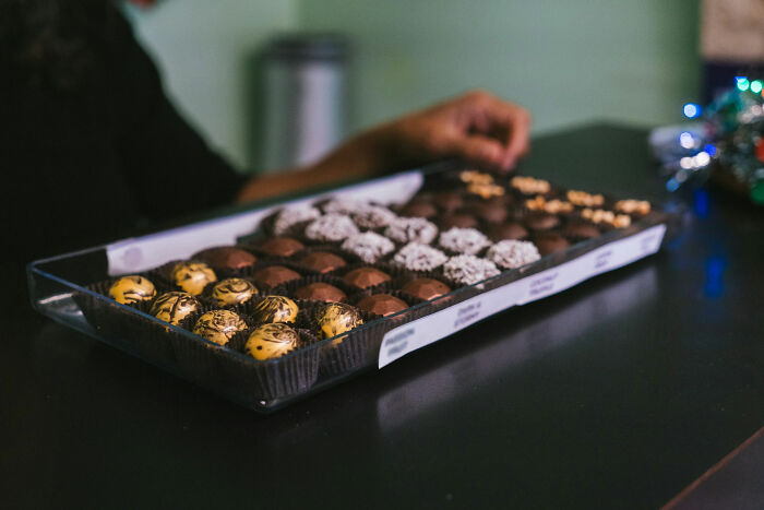 Person reaching for chocolates in a box on a table, illustrating how people took revenge on their bosses. - 3