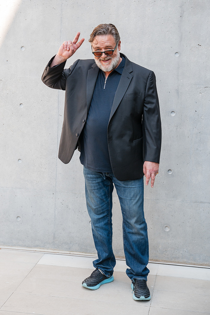 Russell Crowe in a black blazer and jeans showing peace sign, highlighting dramatic weight loss with Ozempic during recent outing. Russell Crowe in a black blazer and jeans showing peace sign, highlighting dramatic weight loss with Ozempic during recent outing.