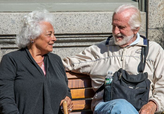 Elderly couple sitting on a bench having a conversation reflecting on married life and relationship struggles.