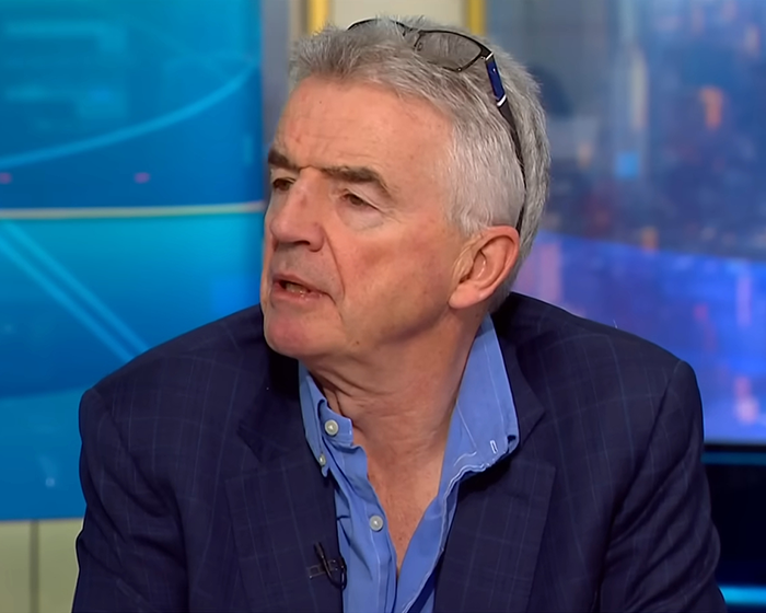 Man in a blue shirt and navy blazer speaking during an interview about Ryanair passenger luggage size issues. - 9