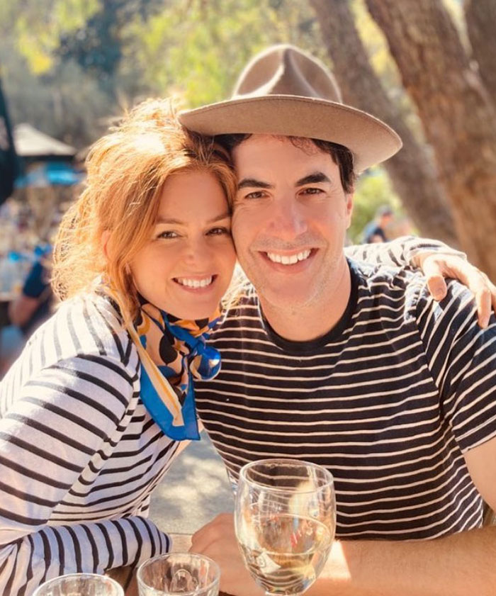 Sacha Baron Cohen and woman smiling outdoors, highlighting Sacha Baron Cohen's ripped transformation after divorce.