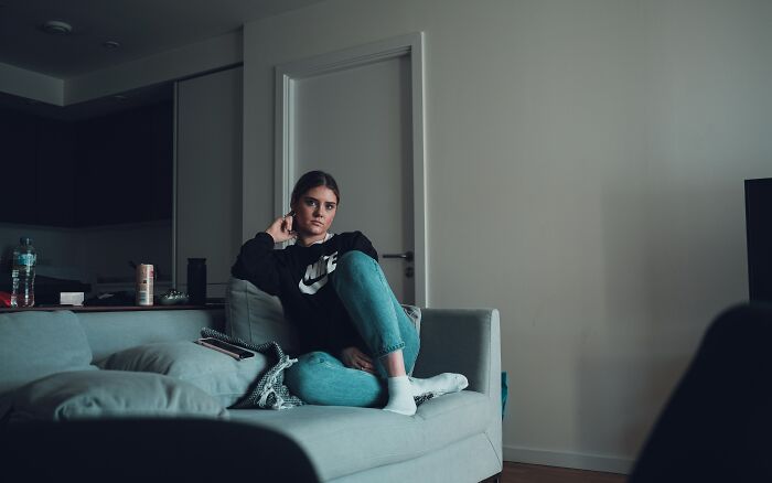 Young woman sitting alone on a couch looking upset, illustrating the pettiest things in breakups and borderline insane reactions.