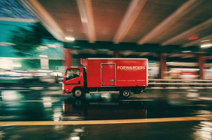 Red delivery truck moving fast at night, illustrating the benefits of working the night shift despite its bad reputation. - 29