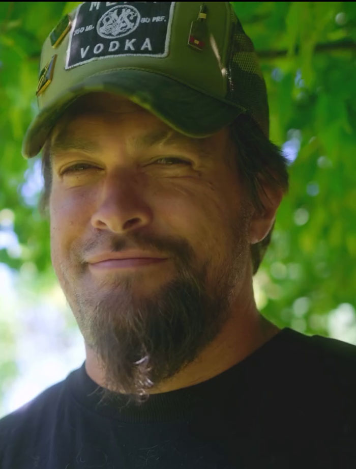 Jason Momoa close-up outdoors wearing a green cap, showing a trimmed beard after shaving his iconic facial hair for fans. - 10