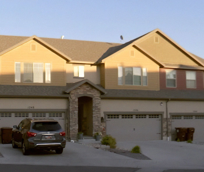 Suburban townhouse exterior with parked car, related to teen sent vile texts before mom and brother found covered in blood.