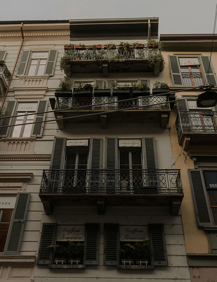 Multi-story building with balconies and plants, evoking peaceful neighbor tales that inspire moving to the woods.