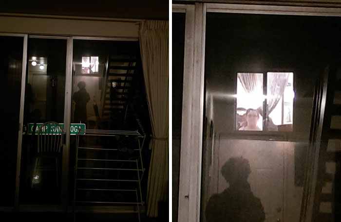 Dimly lit house exterior at night showing window reflections and shadowy figures, evoking neighbor tales in a woods setting.