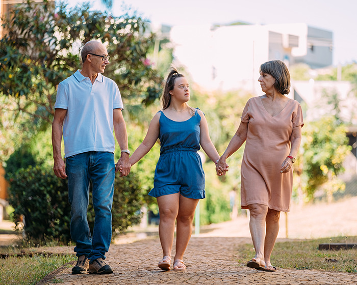 Family walking outdoors holding hands, highlighting breakthrough gene editing for Down Syndrome cure advancements.