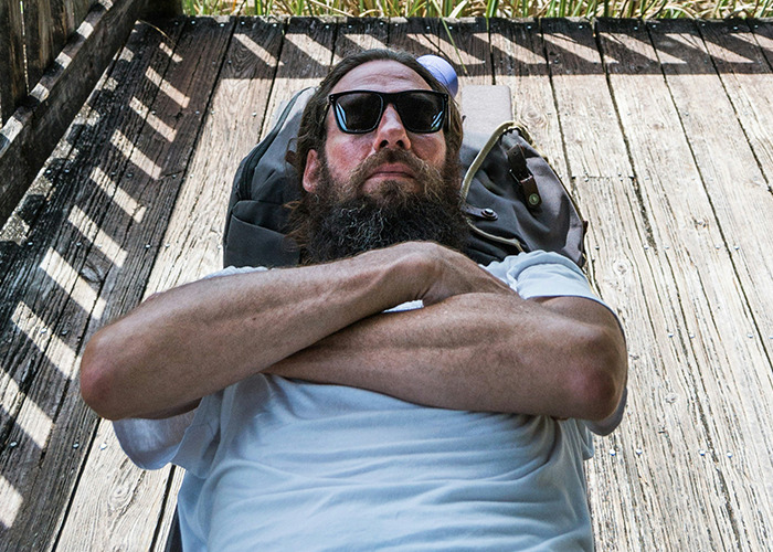 Bearded man wearing sunglasses lying with arms crossed on wooden floor, symbolizing secrets people pray parents never find out. - 34