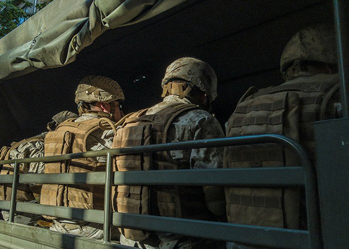 Soldiers in tactical gear sitting closely together inside a military transport vehicle, representing hidden secrets. - 14