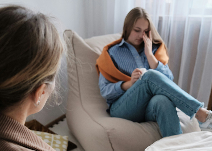 Teen girl looking distressed while sitting on a chair with a woman nearby, reflecting secrets people pray their parents never find out. - 13