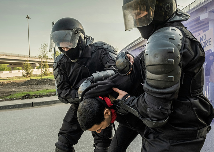 Police officers in riot gear detaining a young man, depicting intense moments related to secrets people pray parents never find out. - 35