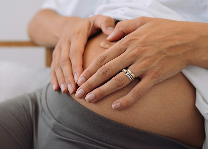 Close-up of hands gently resting on a pregnant belly, symbolizing secrets people pray their parents never find out. - 37