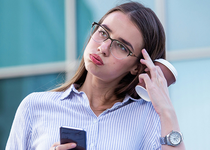 Young woman holding phone and coffee cup, looking thoughtful, representing secrets people pray their parents never find out. - 5