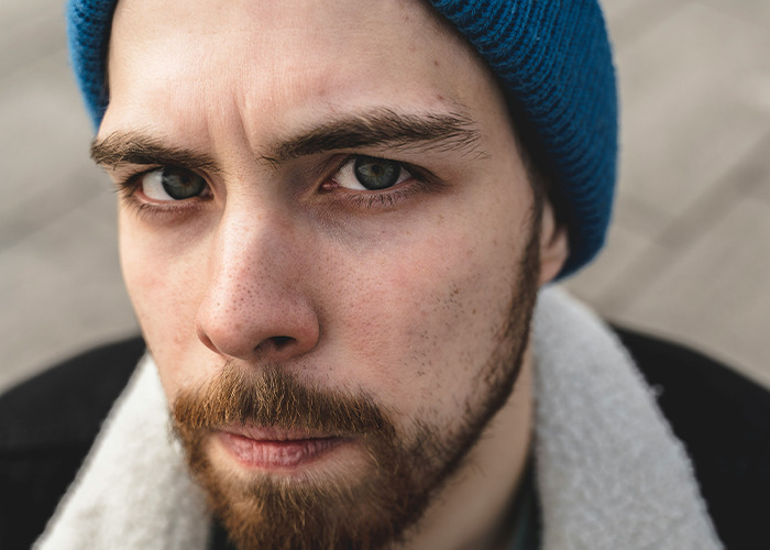 Close-up of a young man wearing a blue beanie with a serious expression hiding secrets from parents. - 8