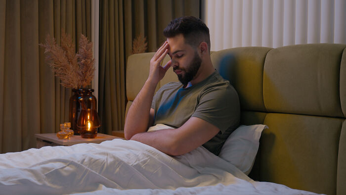 Man sitting in bed with a thoughtful expression, reflecting on impactful sentences that changed people’s lives.