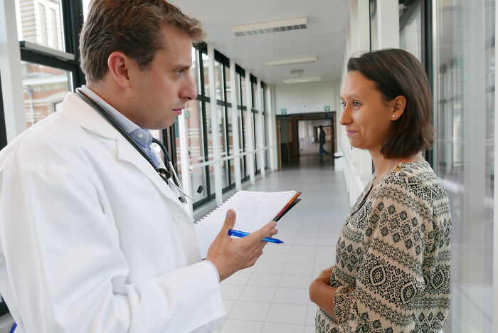 Doctor in white coat discussing important sentences with a patient in a hospital hallway, emphasizing life-changing advice.