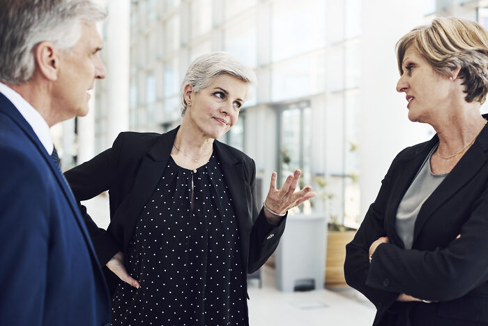 Three business professionals having a serious conversation in a bright office, illustrating sentences that changed lives.