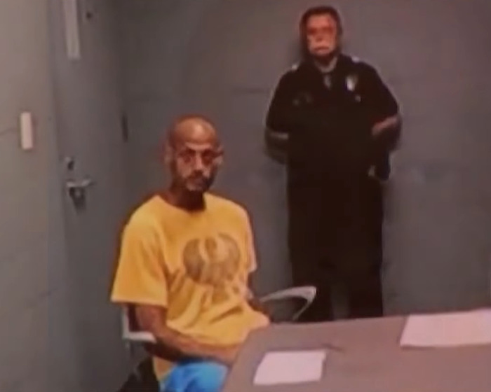 Man in yellow shirt sitting at a table under police watch after viral serial pervert arrested again for public misconduct Man in yellow shirt sitting at a table under police watch after viral serial pervert arrested again for public misconduct