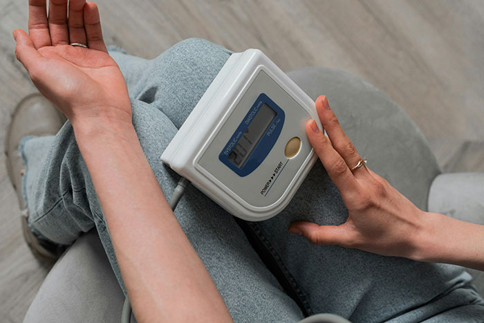 Person checking blood pressure at home, highlighting challenges in diagnosing serious medical conditions early.