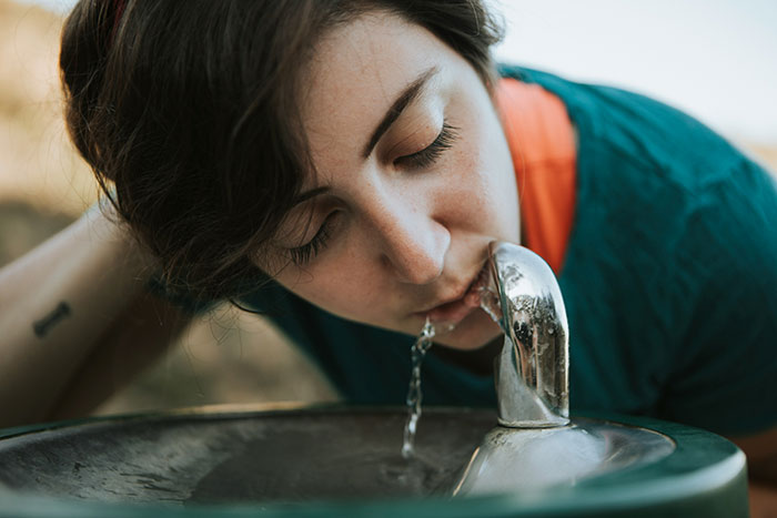 Person drinking water from a public fountain illustrating health awareness of serious medical conditions diagnosis delay.