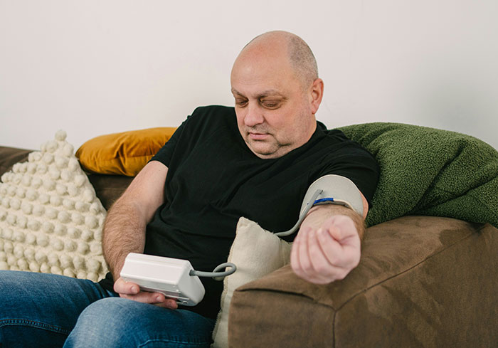Middle-aged man checking blood pressure at home, highlighting serious medical conditions often dismissed and diagnosed late.