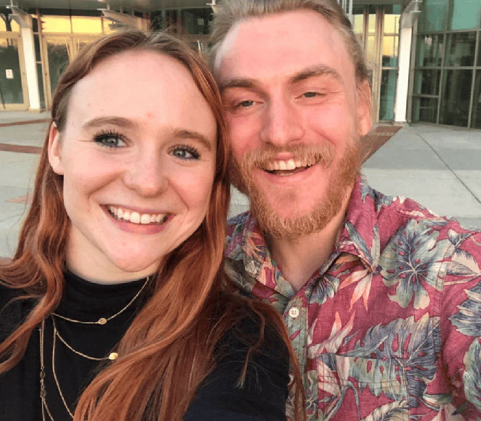 Smiling young people taking a selfie outside a building, unrelated to Virginia councilman set on fire attack news.
