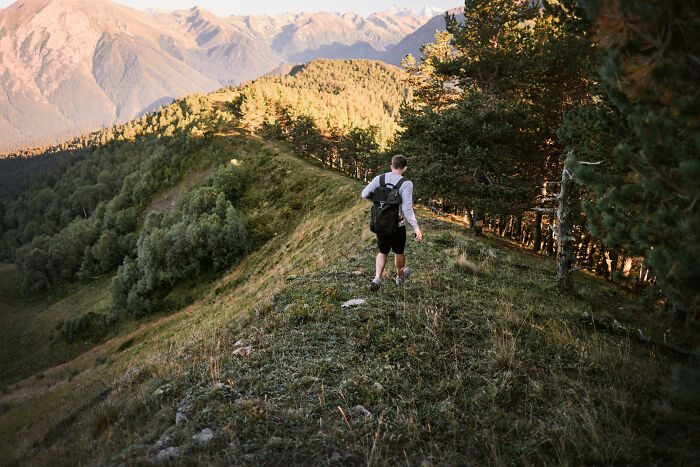Person hiking alone on a mountain ridge in nature, representing signs you grew up sheltered and exploring outside comfort zones.